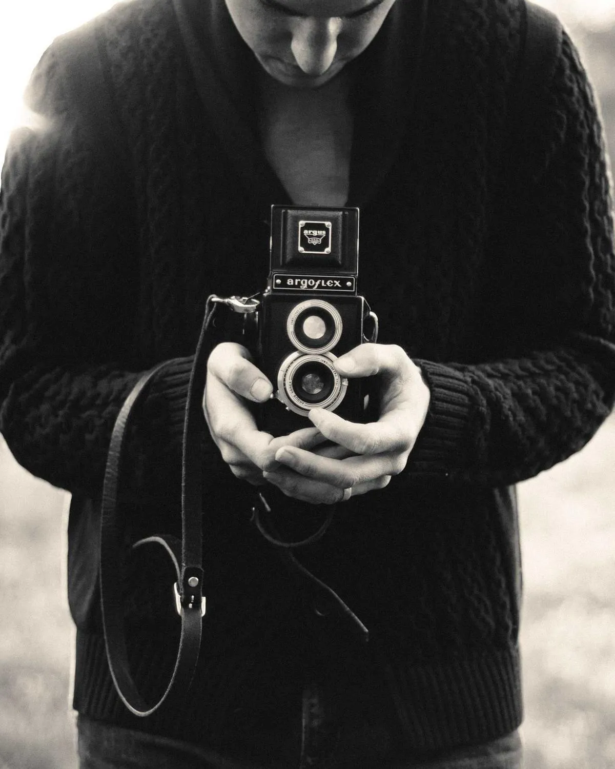 Black-and-white portrait of a person holding a vintage twin-lens camera